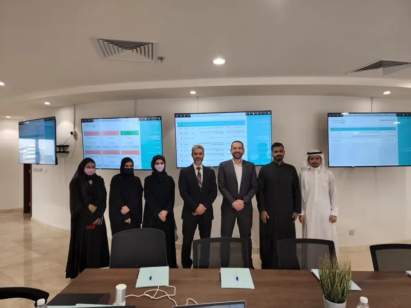 Hajj season PMO team in the program war-room with live dashboards tracking phases, risks and escalations